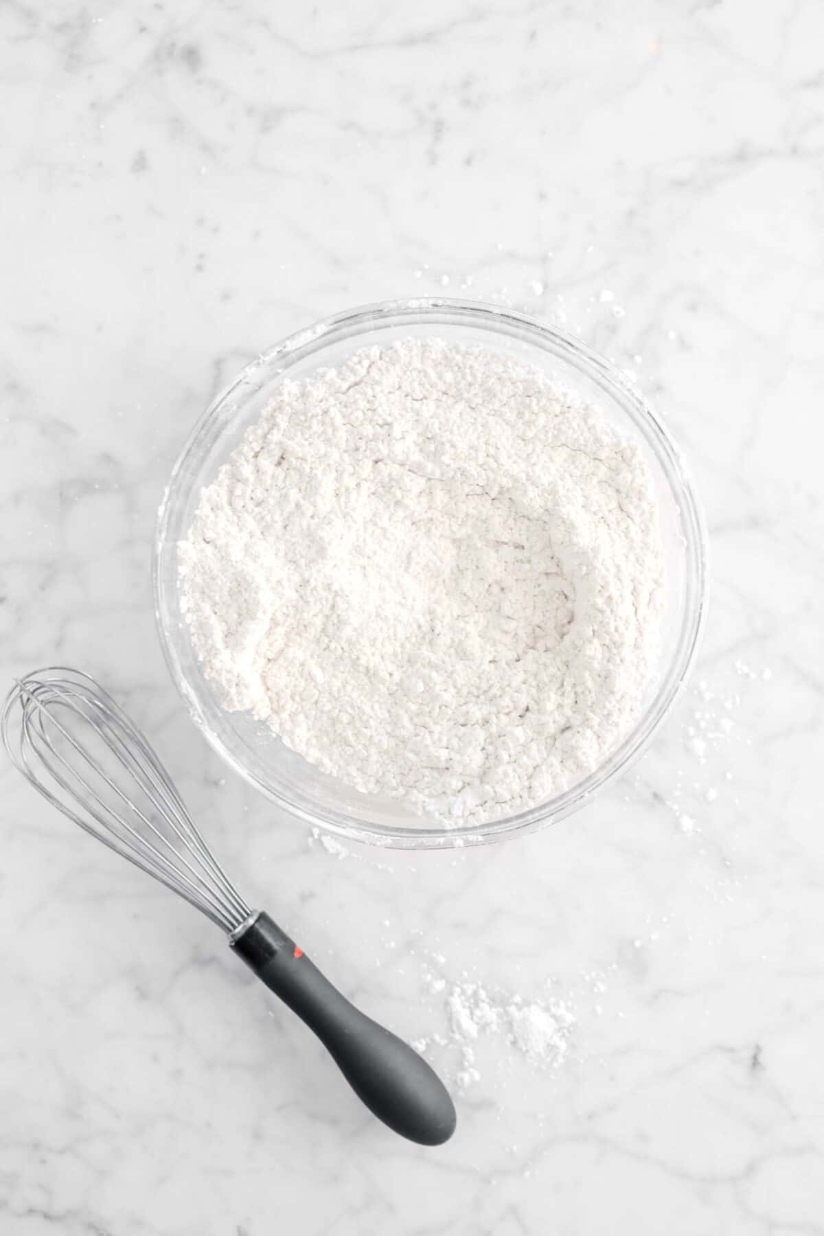powdered sugar and spice whisked together in glass bowl with whisk next to it