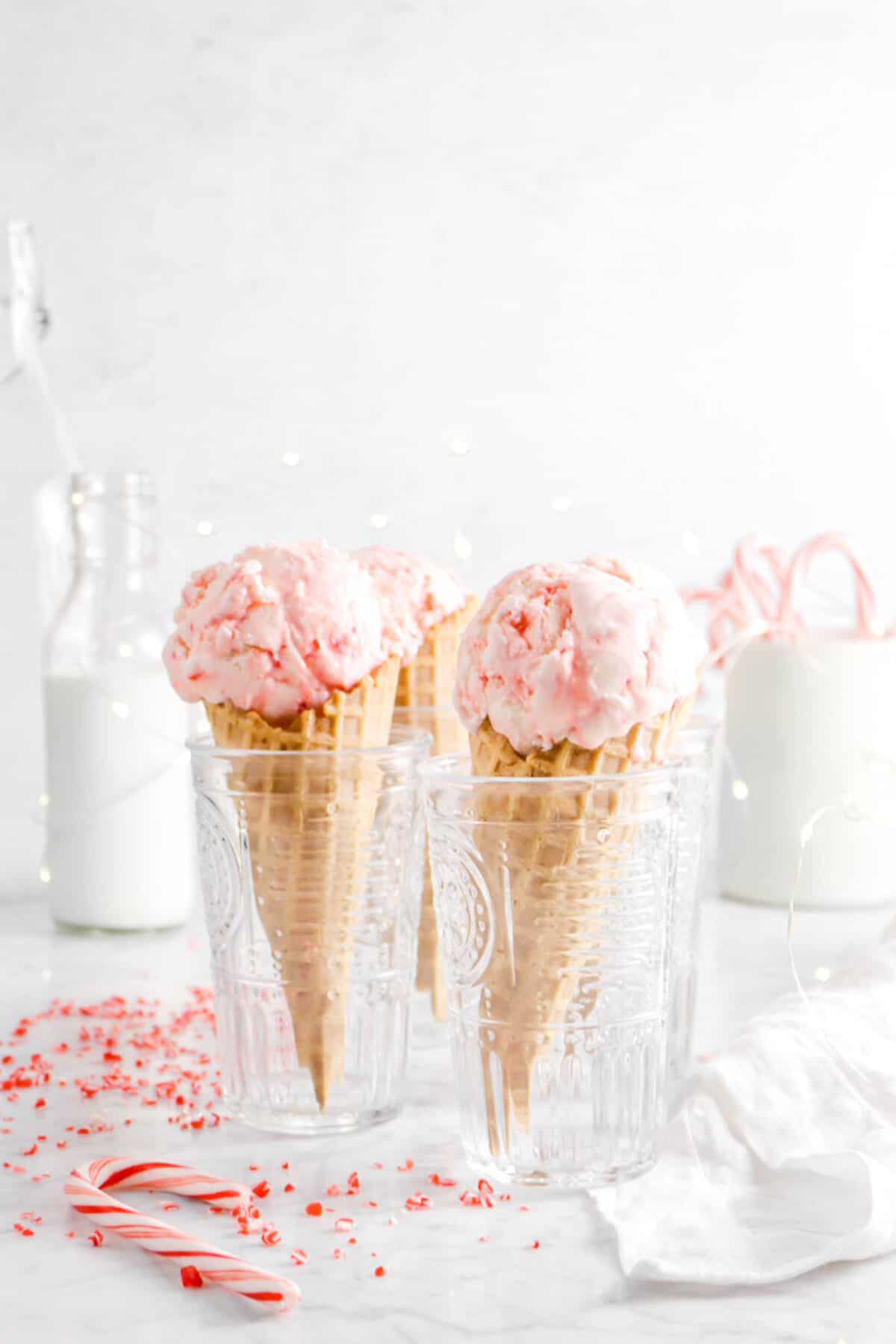 four peppermint ice cream cones with milk, fairy lights, and candy canes