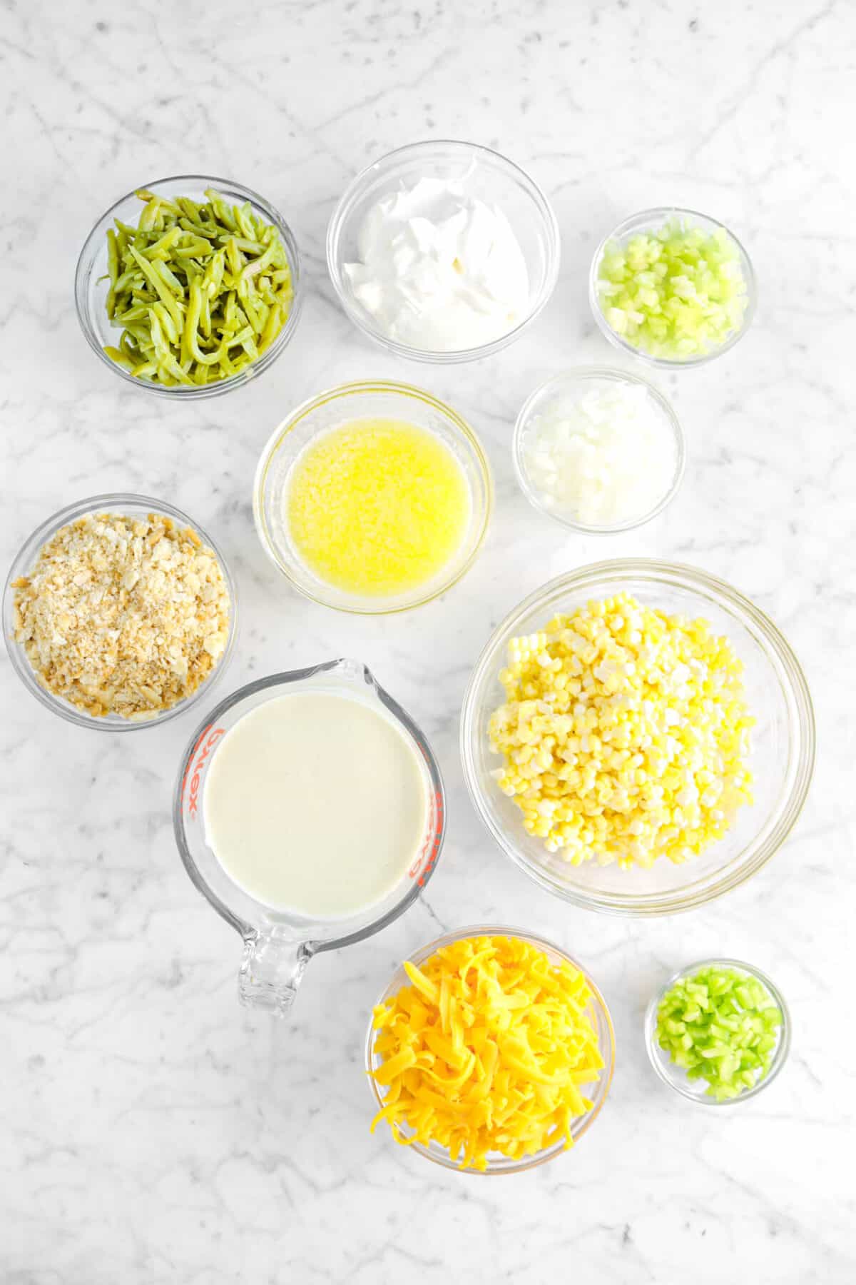 green beans, sour cream, chopped celery, chopped onion, butter, crackers, corn, cream of celery soup, cheddar, and bell pepper in glass bowls