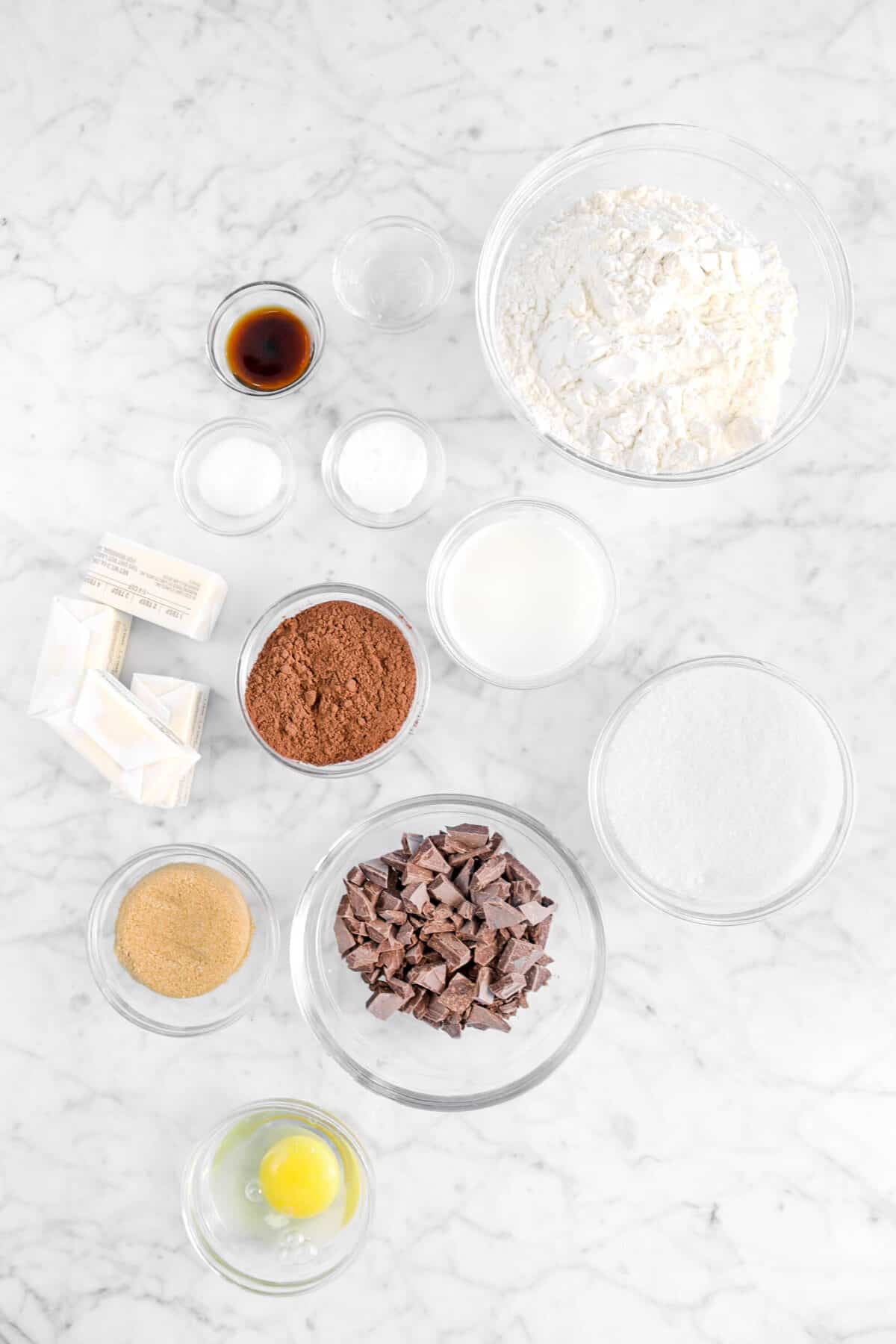 flour, peppermint oil, vanilla, salt, baking soda, milk, sugar, cocoa powder, butter, chocolate chunks, brown sugar, and egg in glass bowls