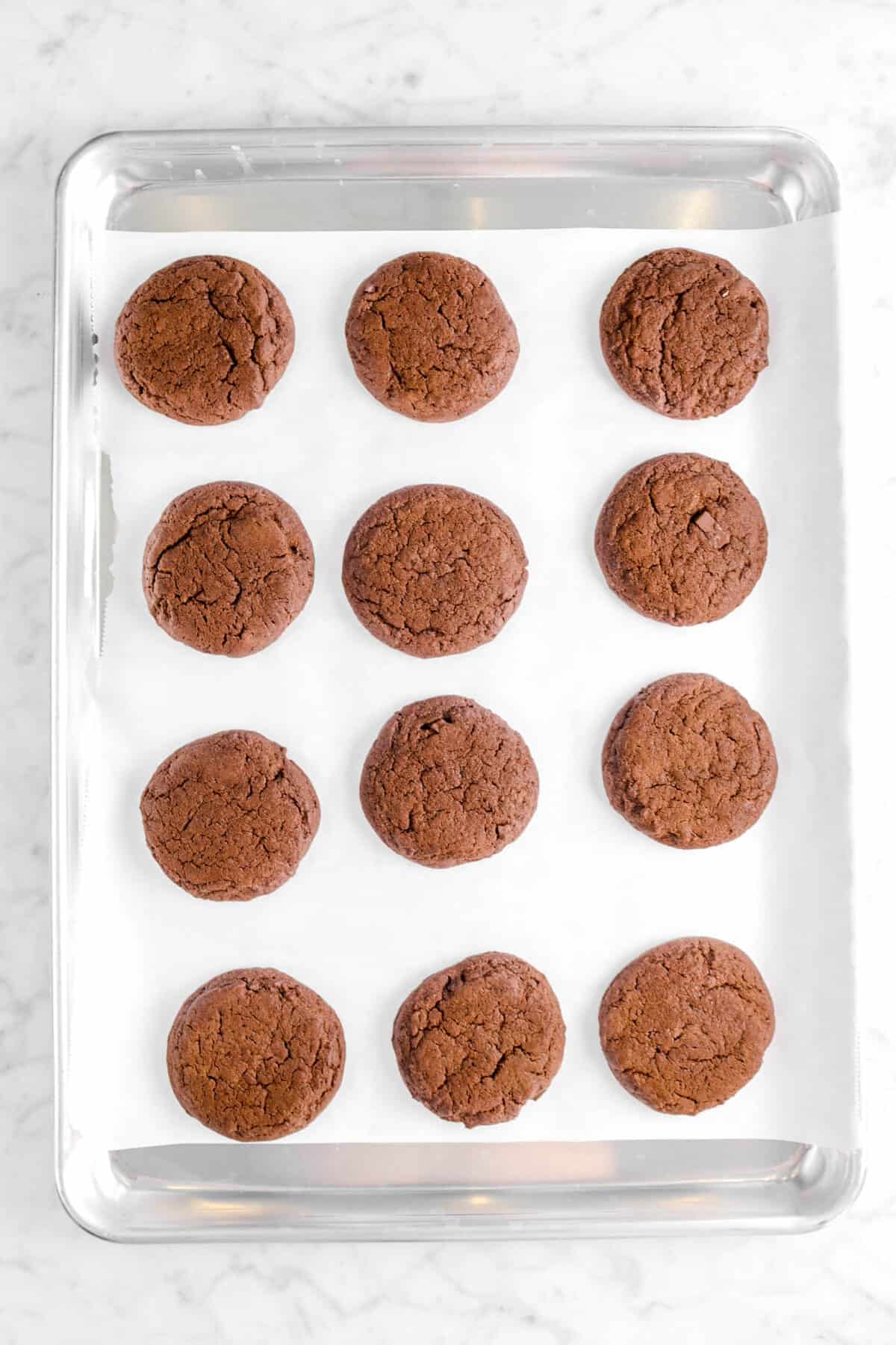 twelve baked chocolate cookies on a baking sheet
