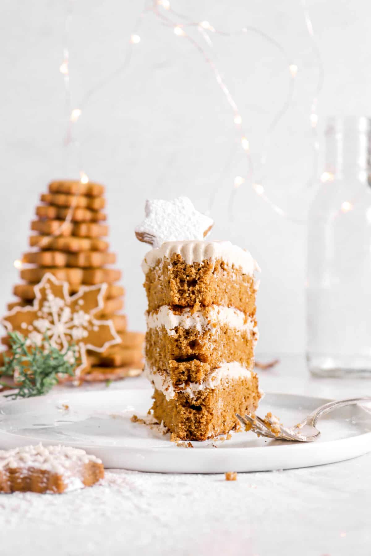 slice of gingerbread cake on a white plate with a fork and cookies l