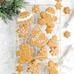 iced gingerbread cookies on gold cooling rack with napkin, greenery, lights, and piping bag