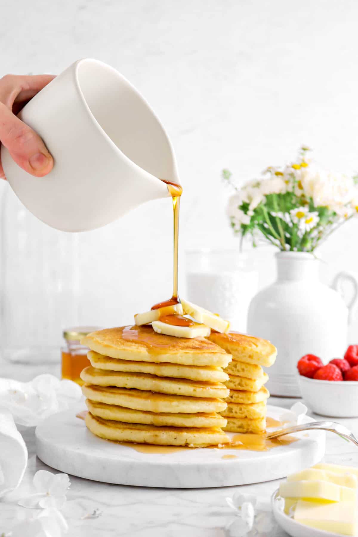 syrup being poured on stacked buttermilk pancakes