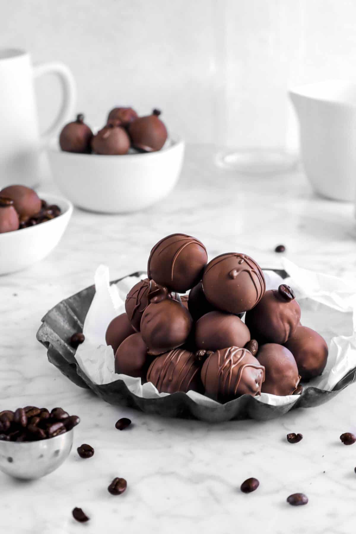 stacked coffee truffles on lined pan with coffee beans and more truffles behind