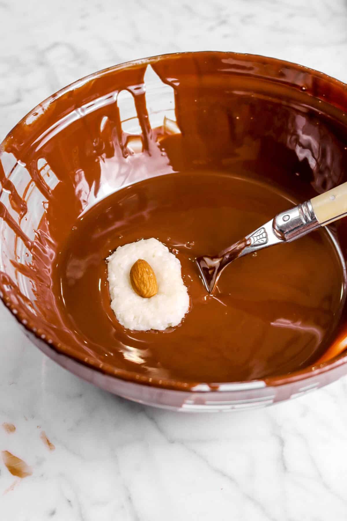 coconut filling in melted chocolate with a fork