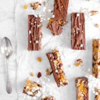 eight granola bars on parchment paper with flowers, flaked salt, and a spoon