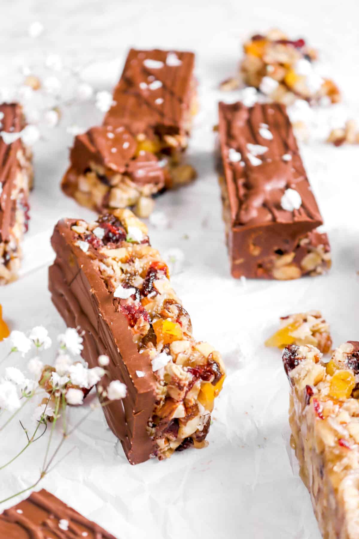 granola bar on its side on parchment paper with flowers and four granola bars around it
