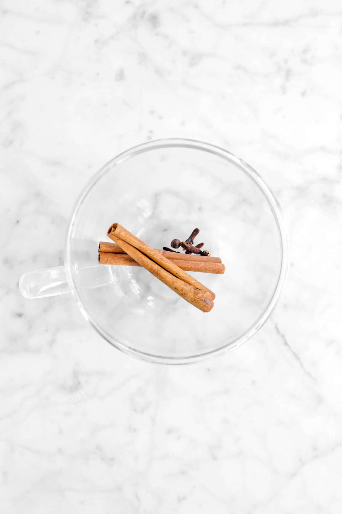 cinnamon sticks and cloves in a glass