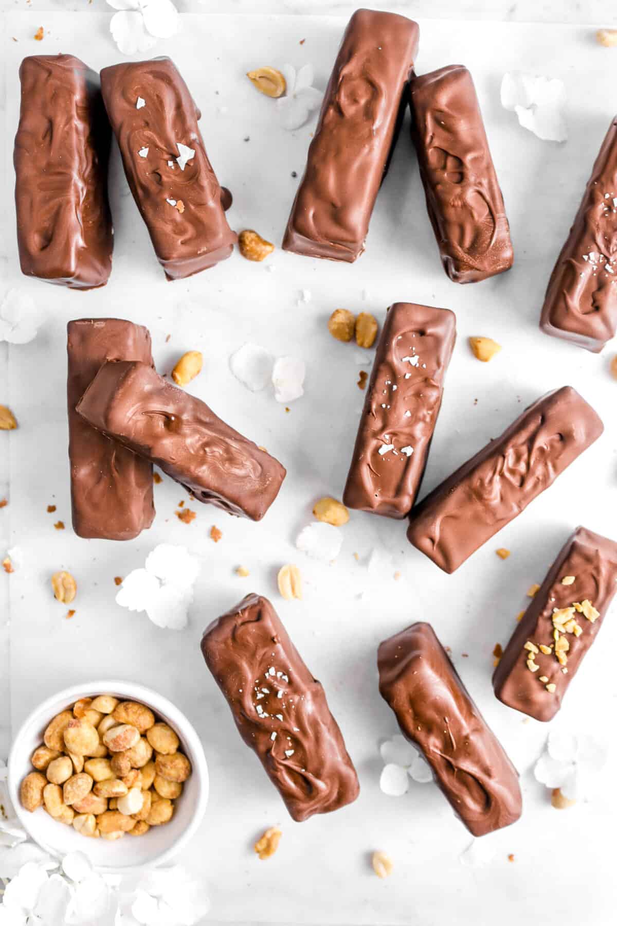 overhead shot of snickers candy bars on parchment with peanuts and flowers