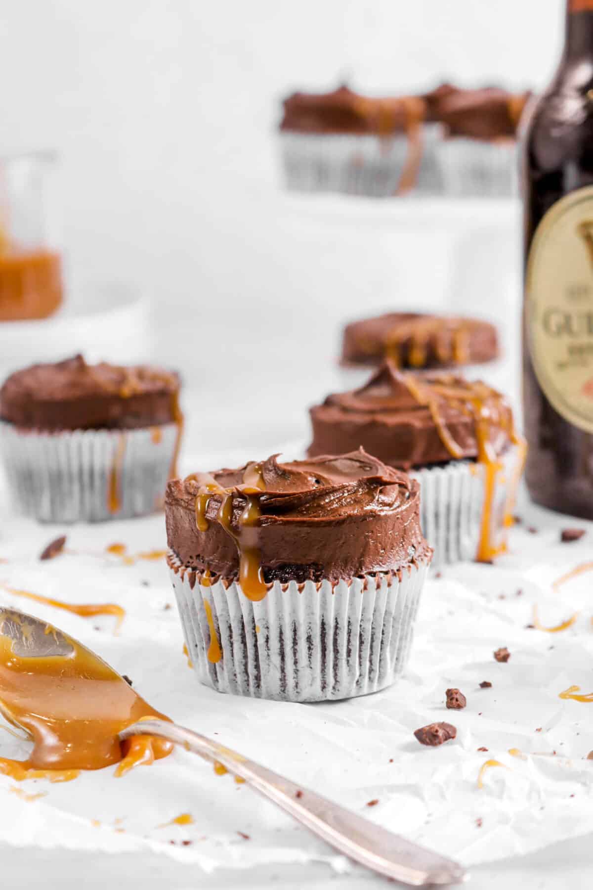 close up of guinness chocolate cupcake with spoonful of caramel with more cupcakes behind