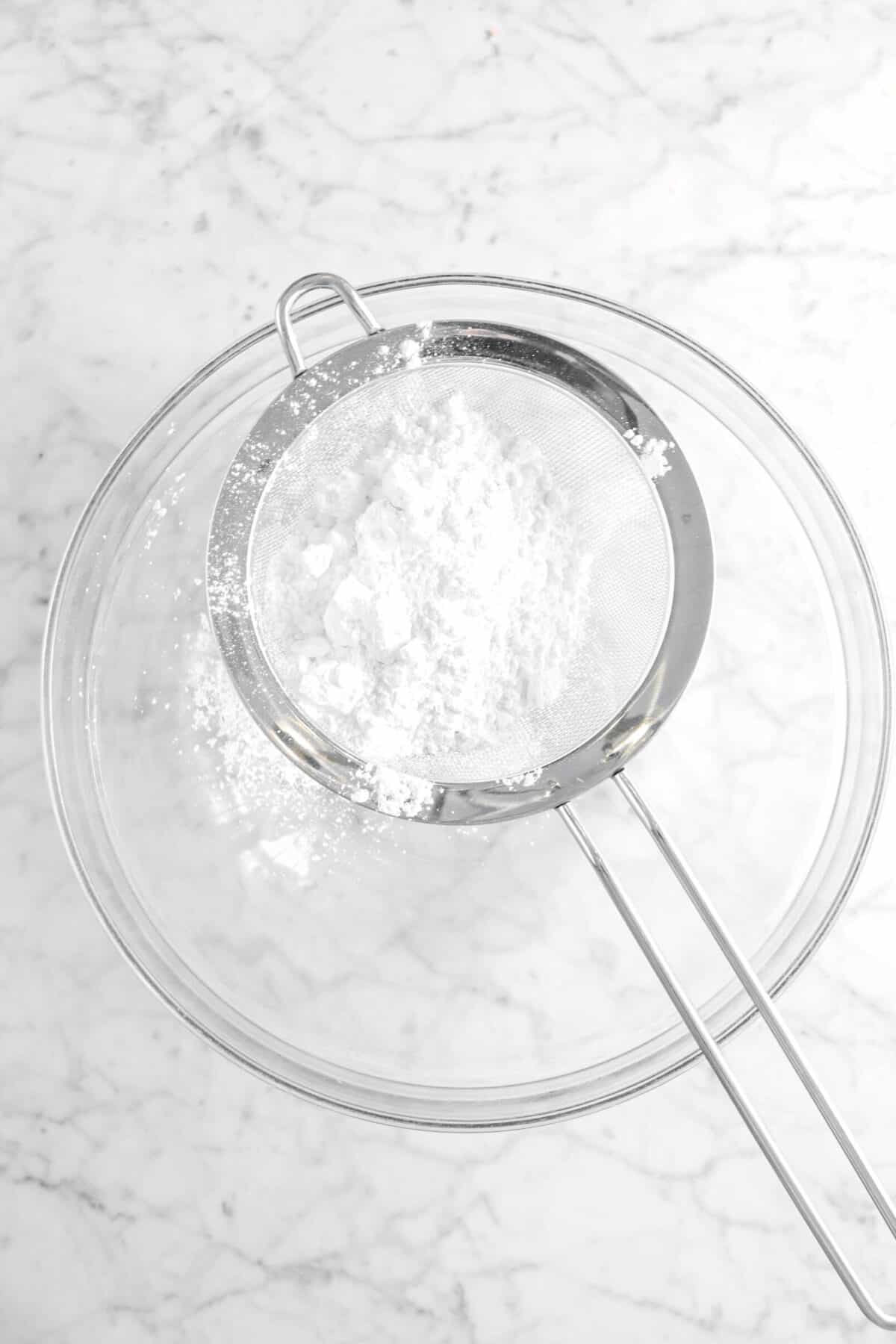 powdered sugar being sifted into glass bowl