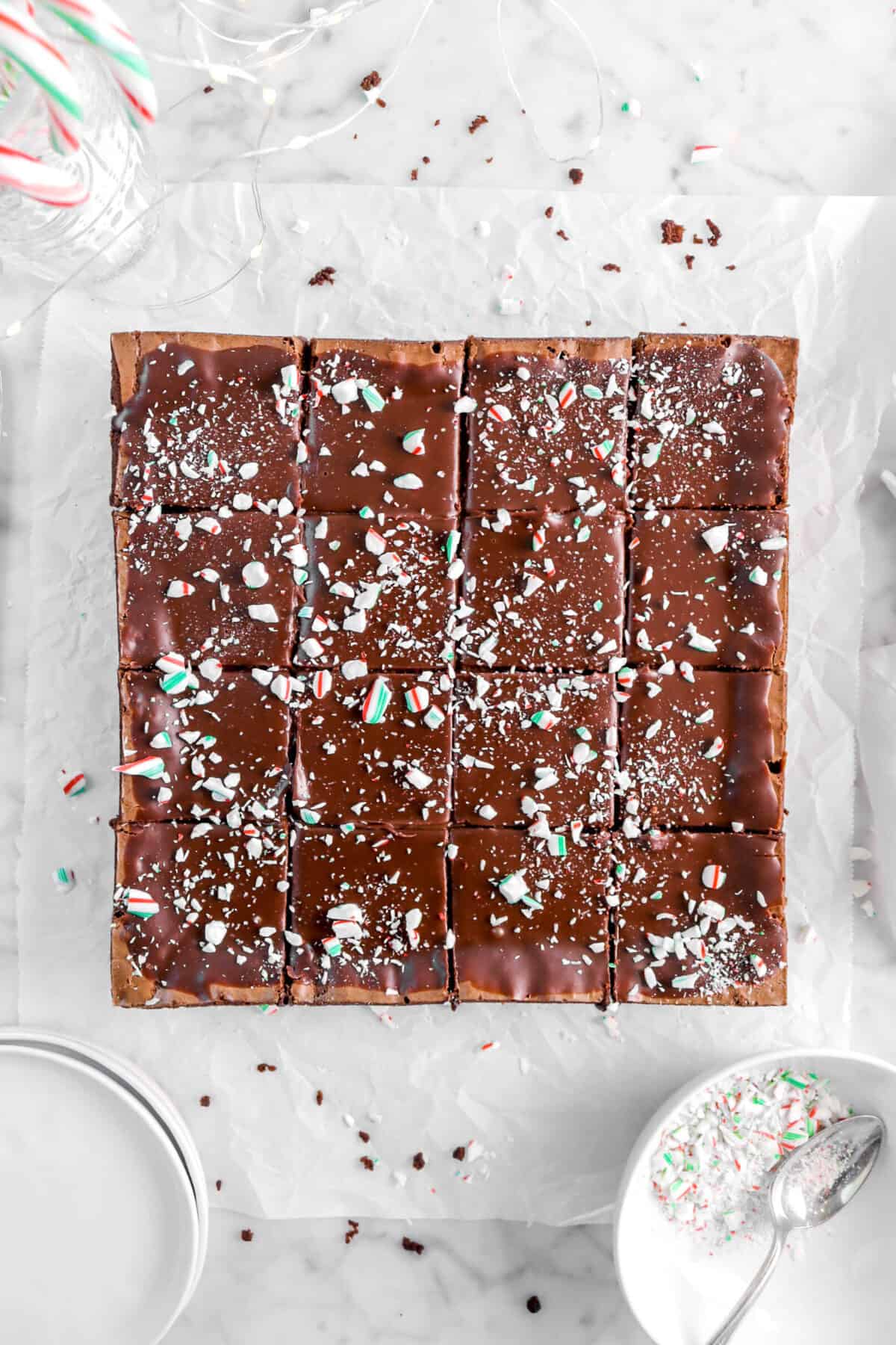 overhead shot of sliced brownies on parchment paper with brown of crushed candy canes