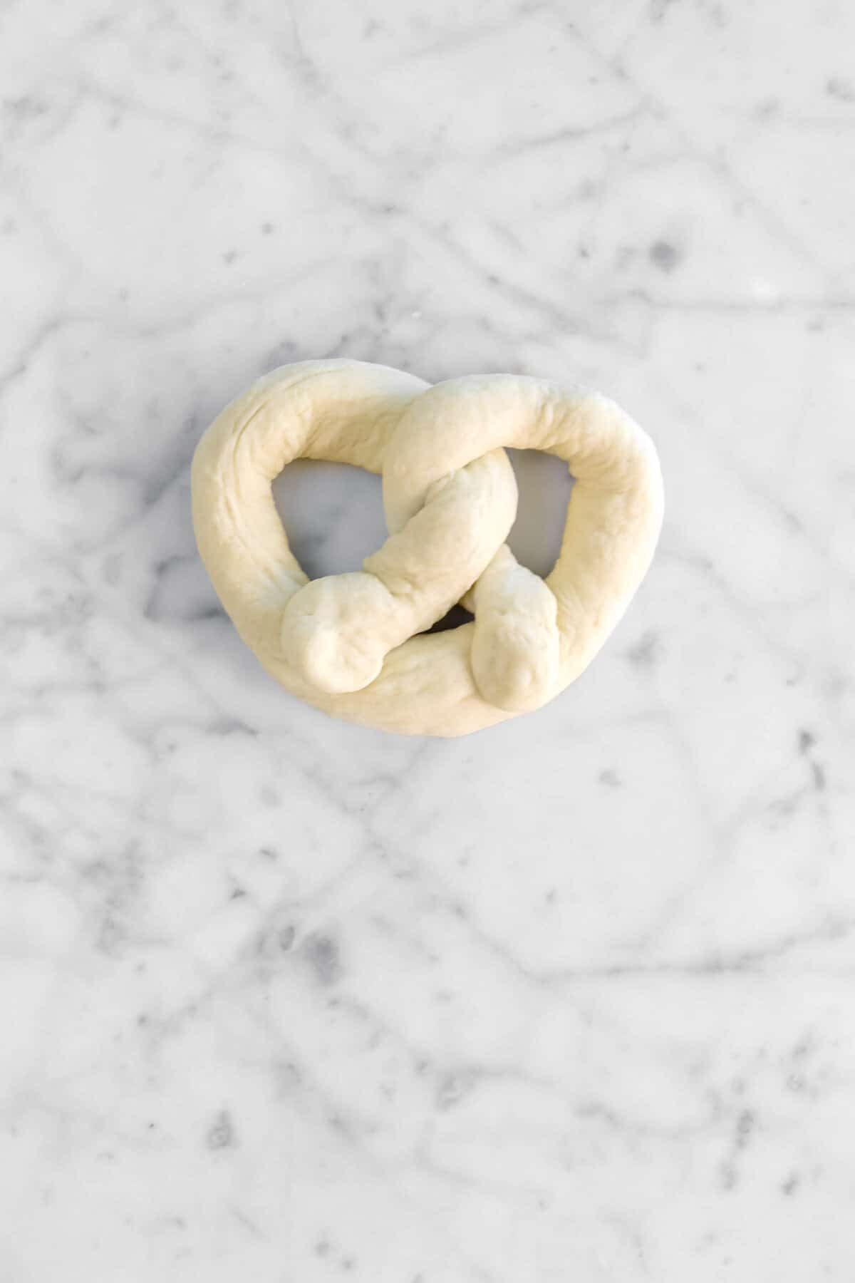 dough shaped like a pretzel on marble counter