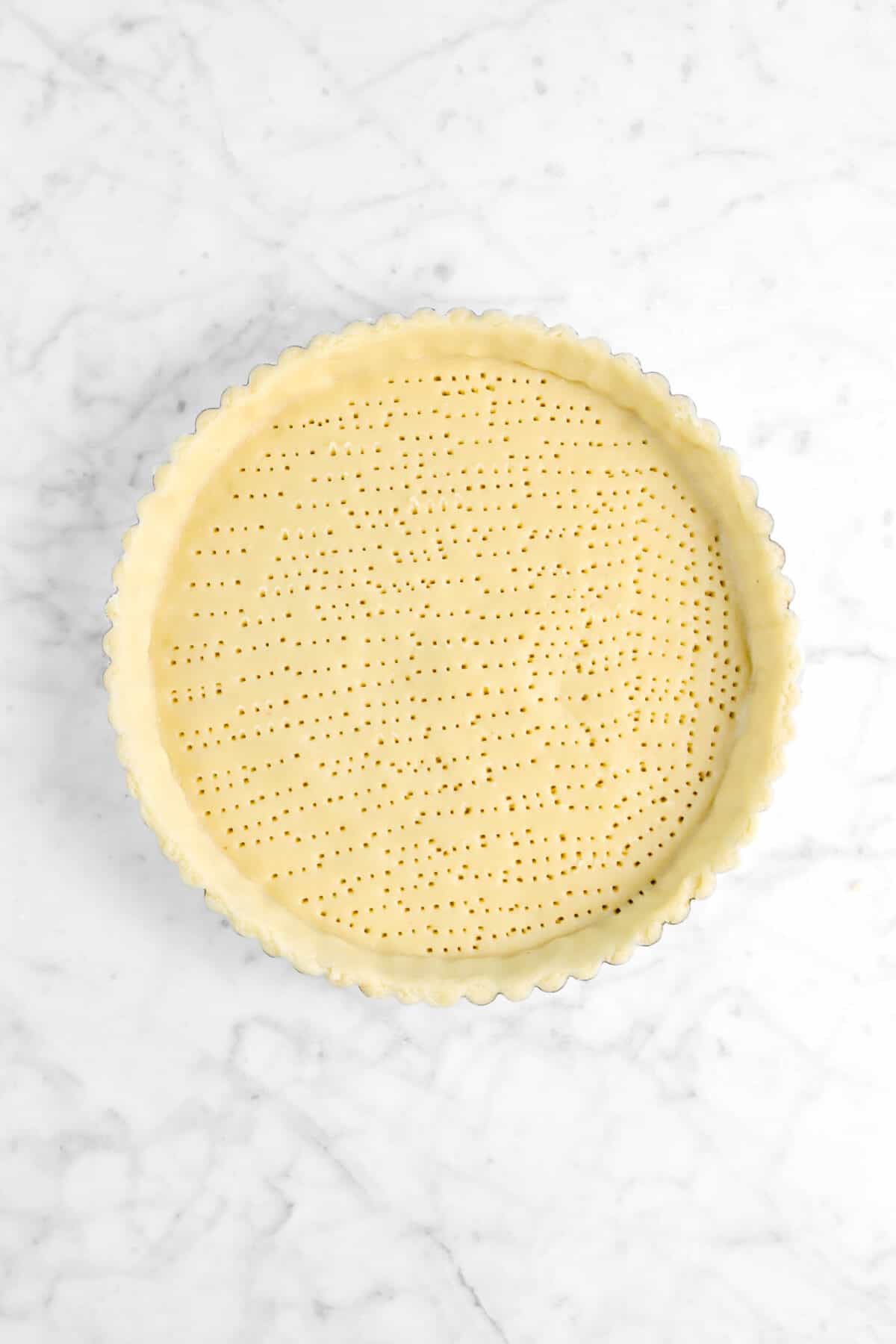 dough in tart pan with bottom pricked with holes