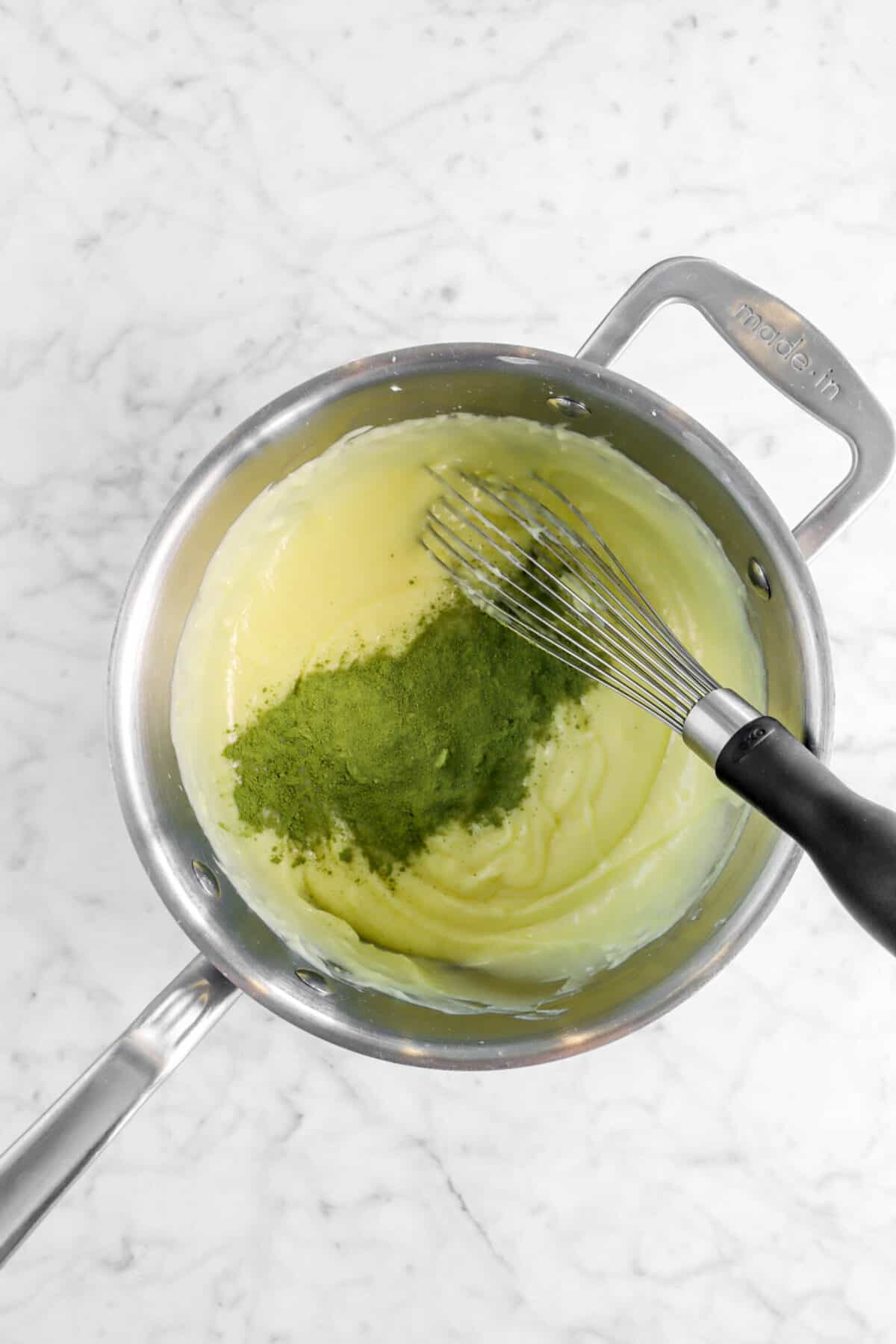 matcha added to custard in a pot with a whisk