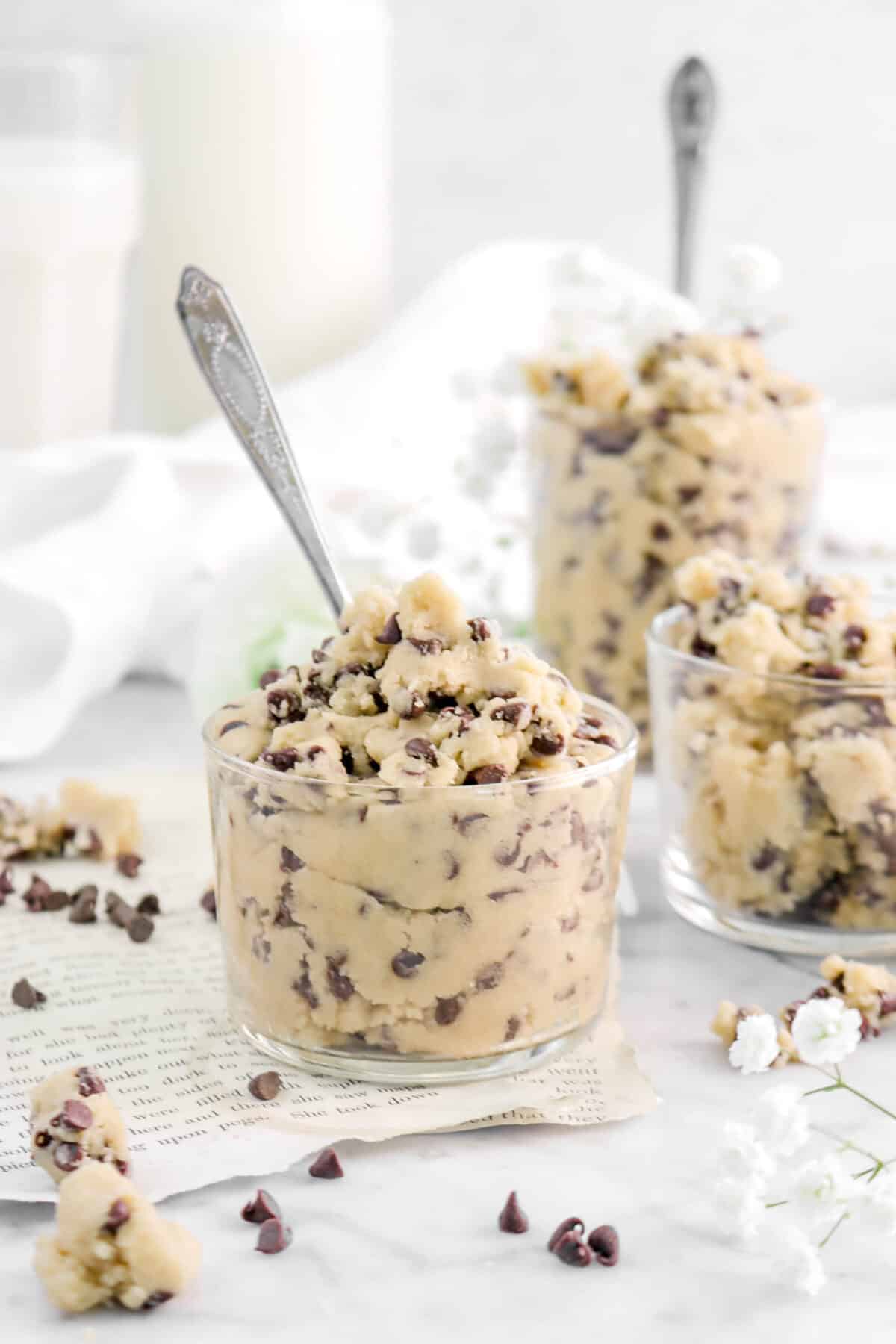 cookie dough in a small glass with spoon inside on book pages