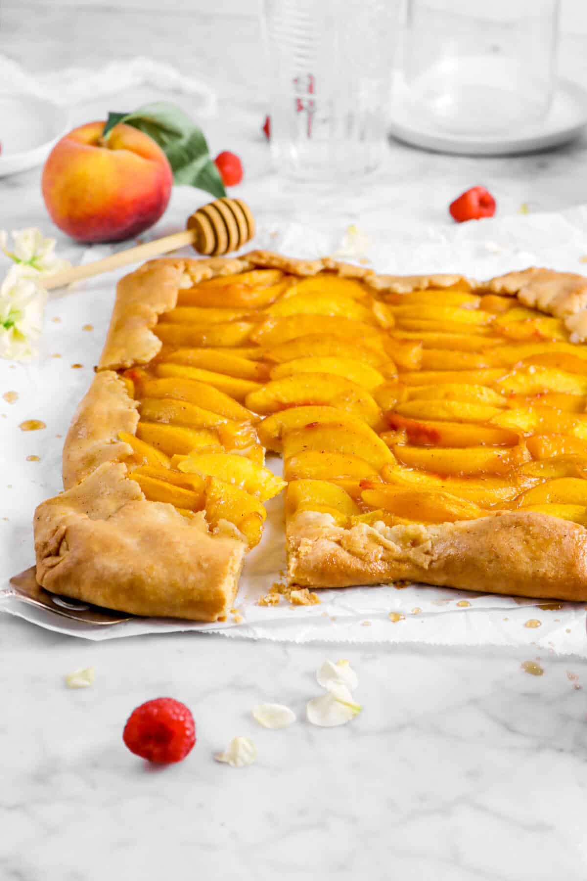 front shot of peach galette with a slice being pulled out