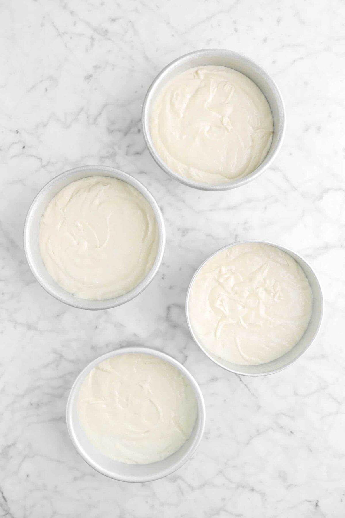 cake batter in four small round cake pans