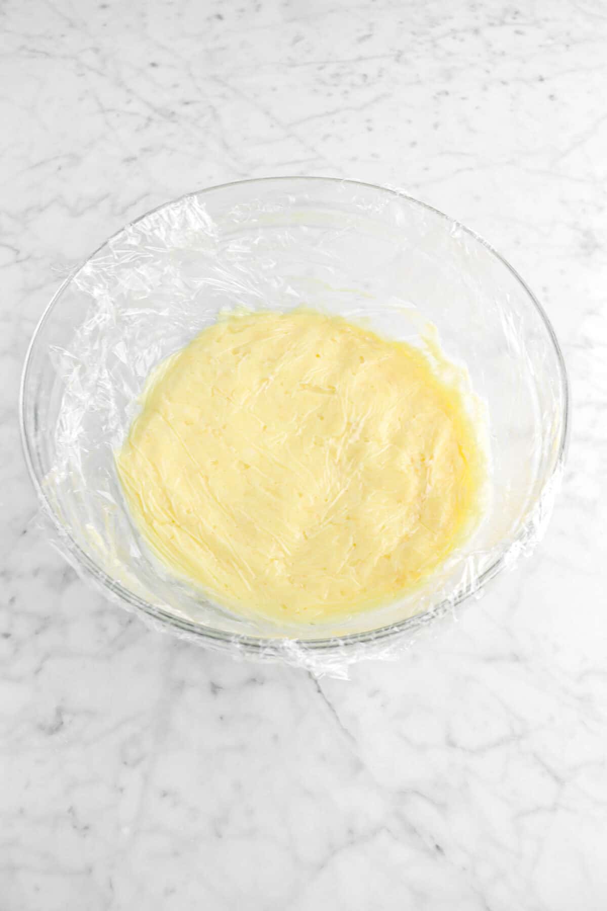 plastic wrap covering pastry cream in a glass bowl