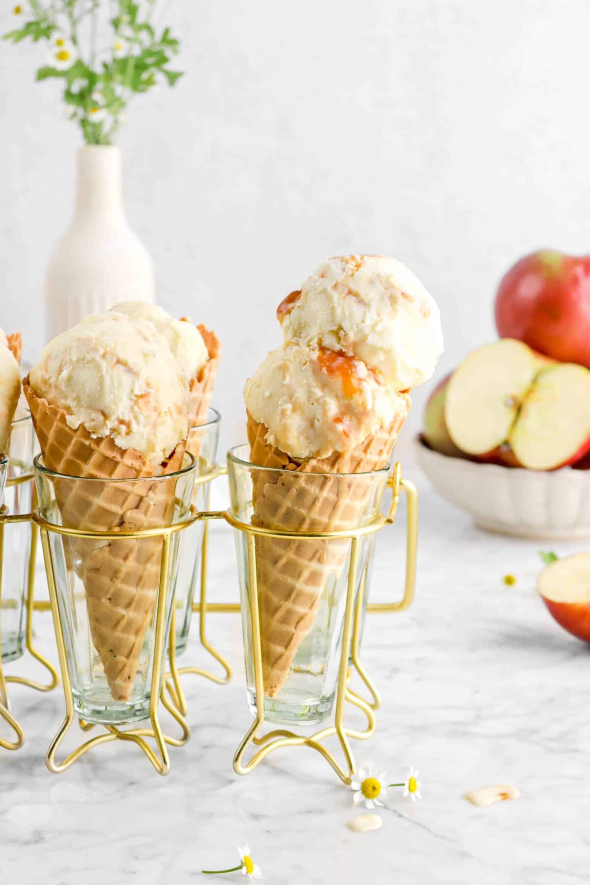 caramel apple ice cream in waffle cones with apples behind