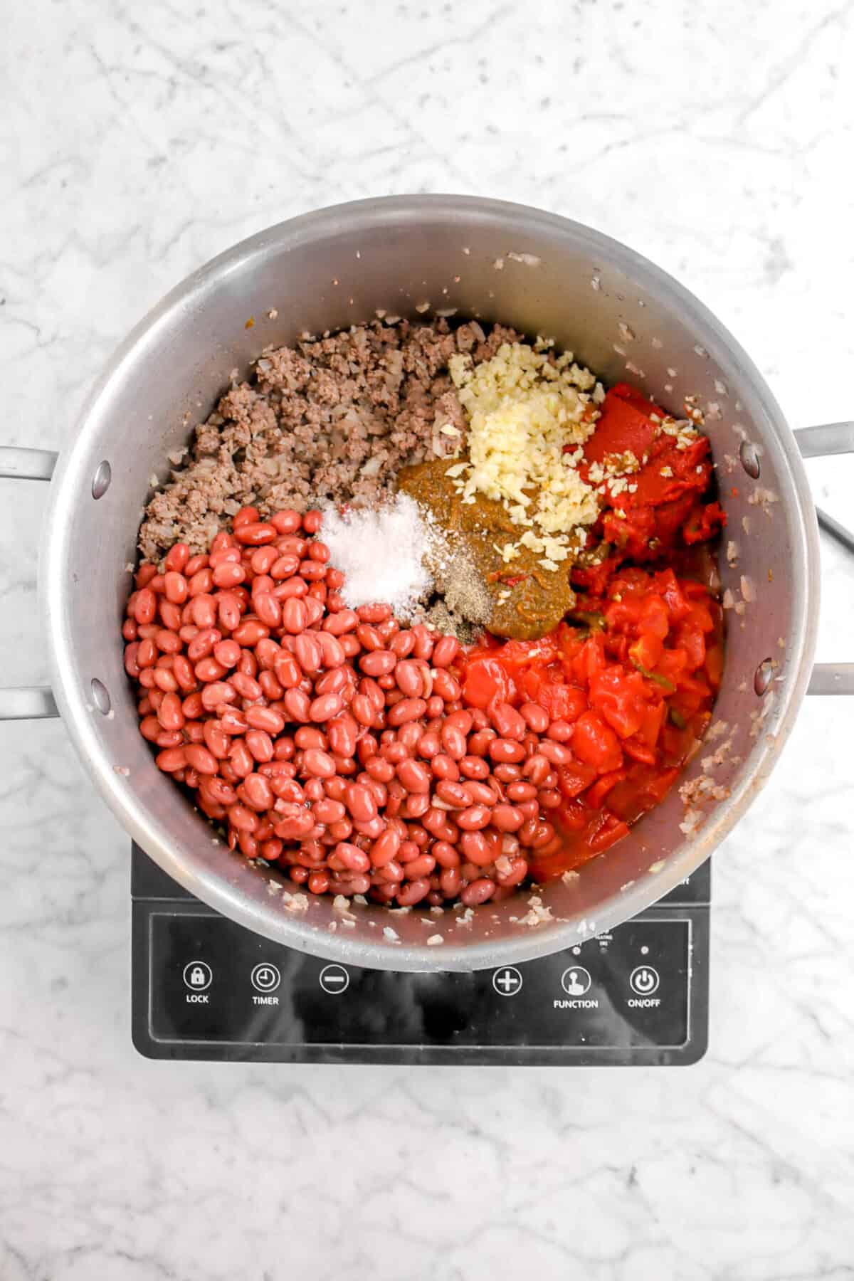 beef mixture in pot with red beans, tomatoes, salt, pepper, chili paste, garlic, and tomato paste