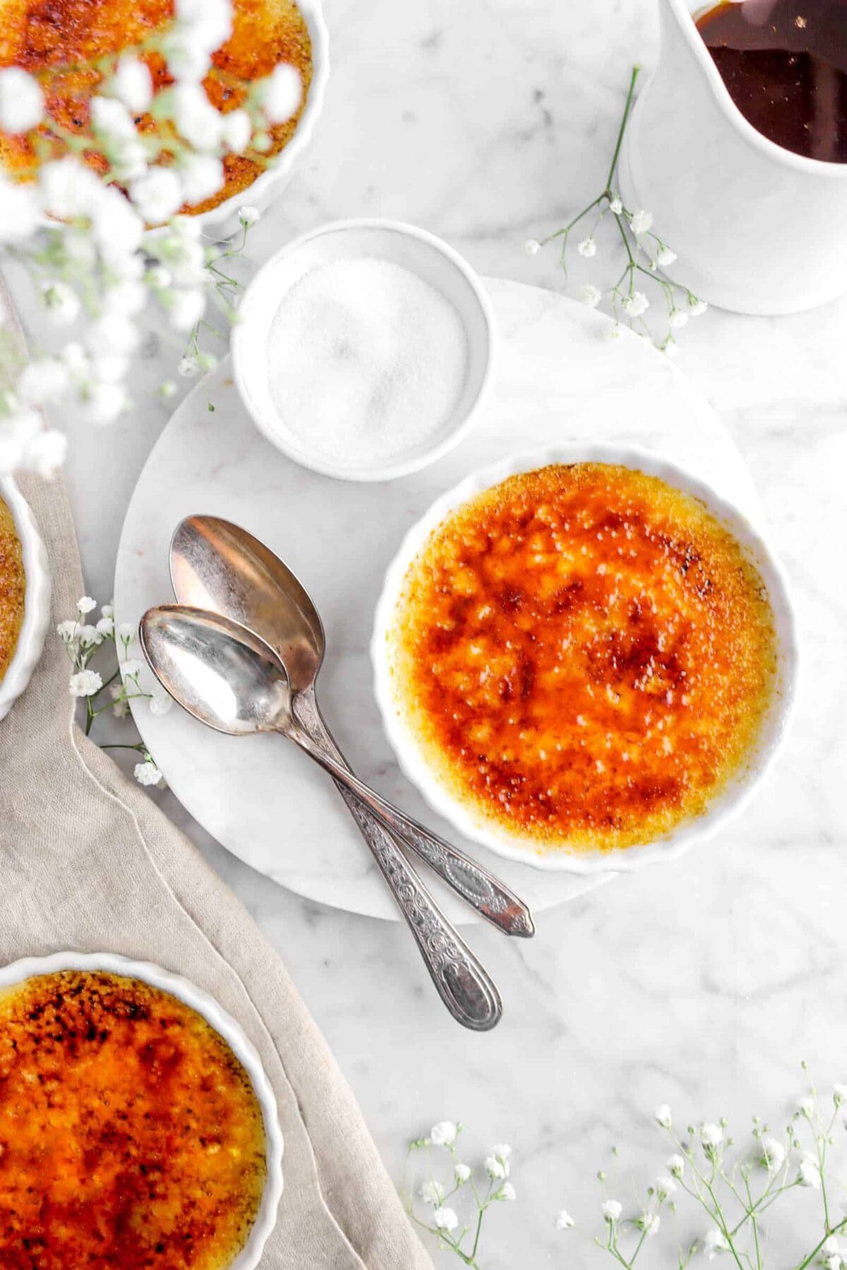 overhead shot of creme brulee with flowers and spoons