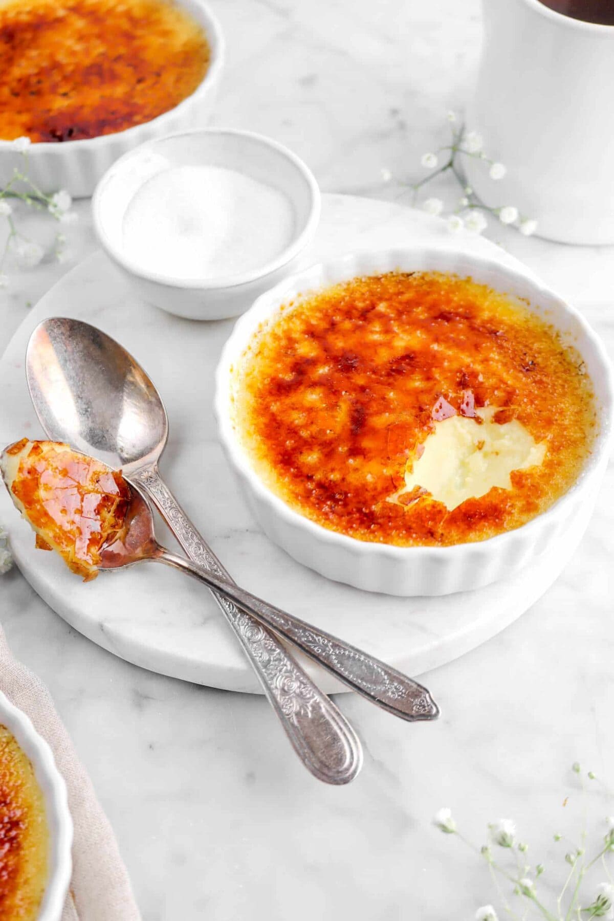 side shot of creme brulee with a spoonful of it next to the ramekin