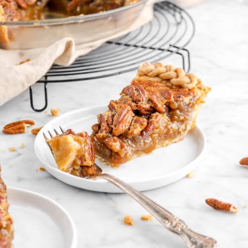 slice of pecan pie on white plate with fork in front