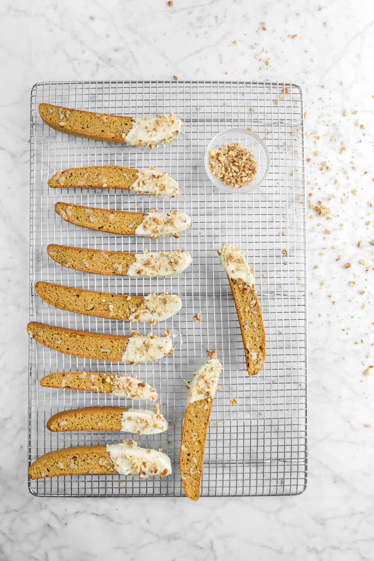 eleven dipped biscotti's on wire cooling rack with walnuts sprinkled on top
