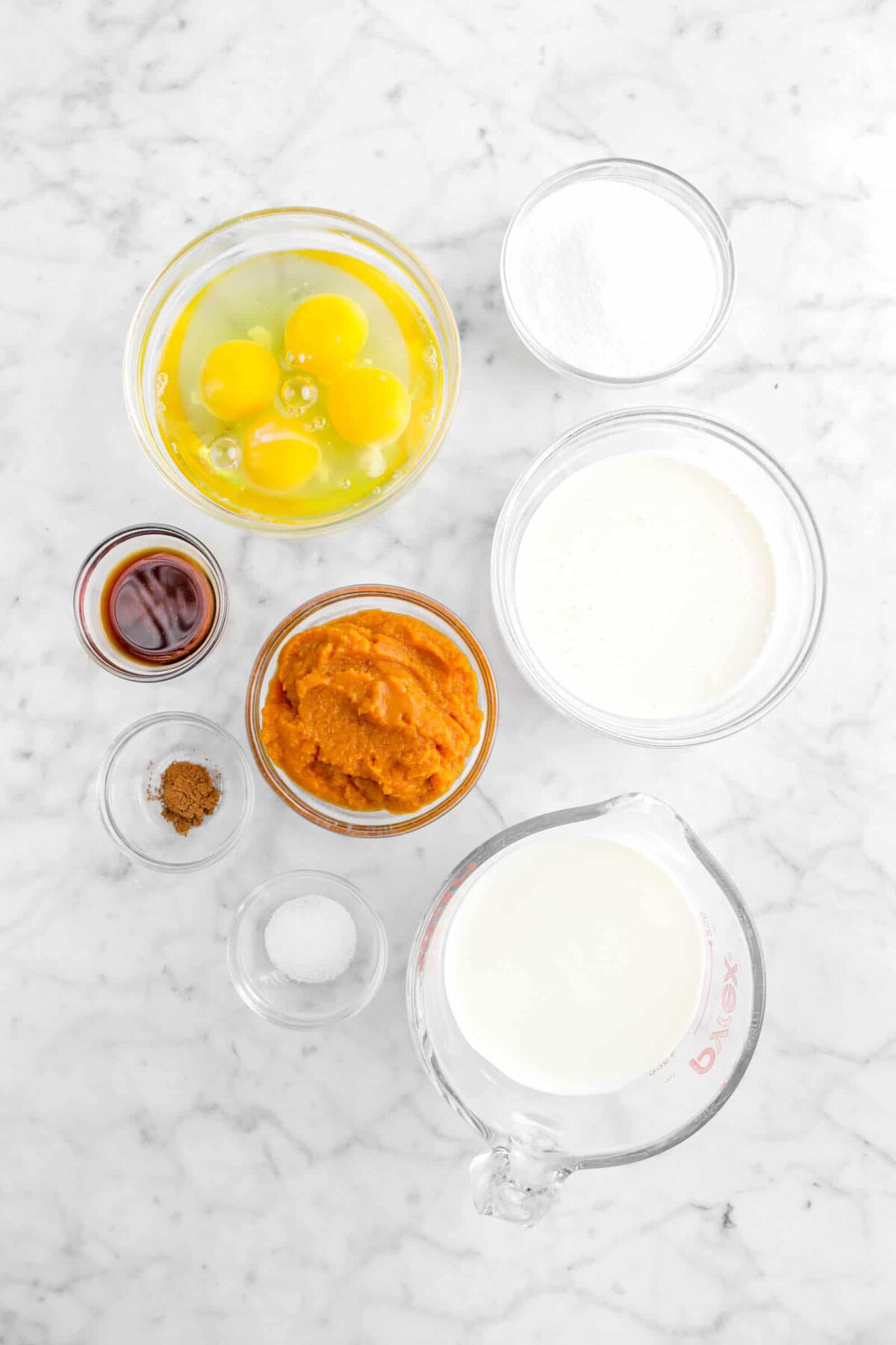 eggs, sugar, milk, heavy cream, pumpkin, vanilla, pumpkin pie spice, and salt on marble counter