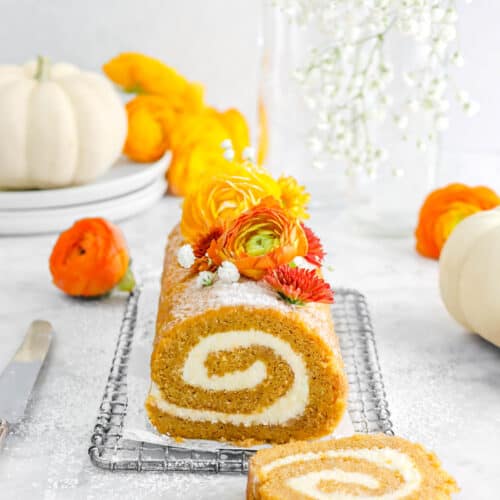 pulled back photo of pumpkin roll with slice laying in front