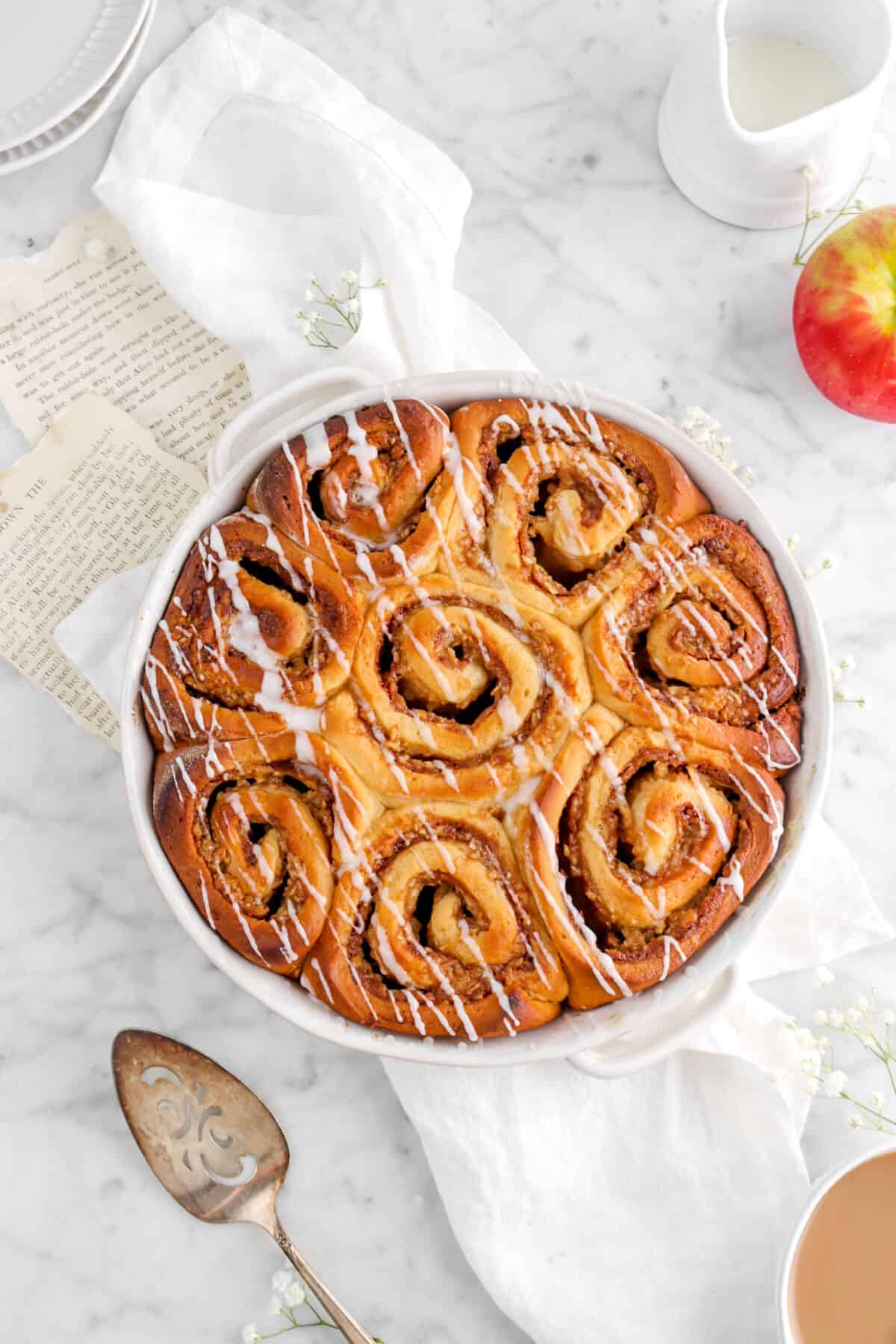 overhead shot of eight apple rolls on white napkin with two book pages and flowers