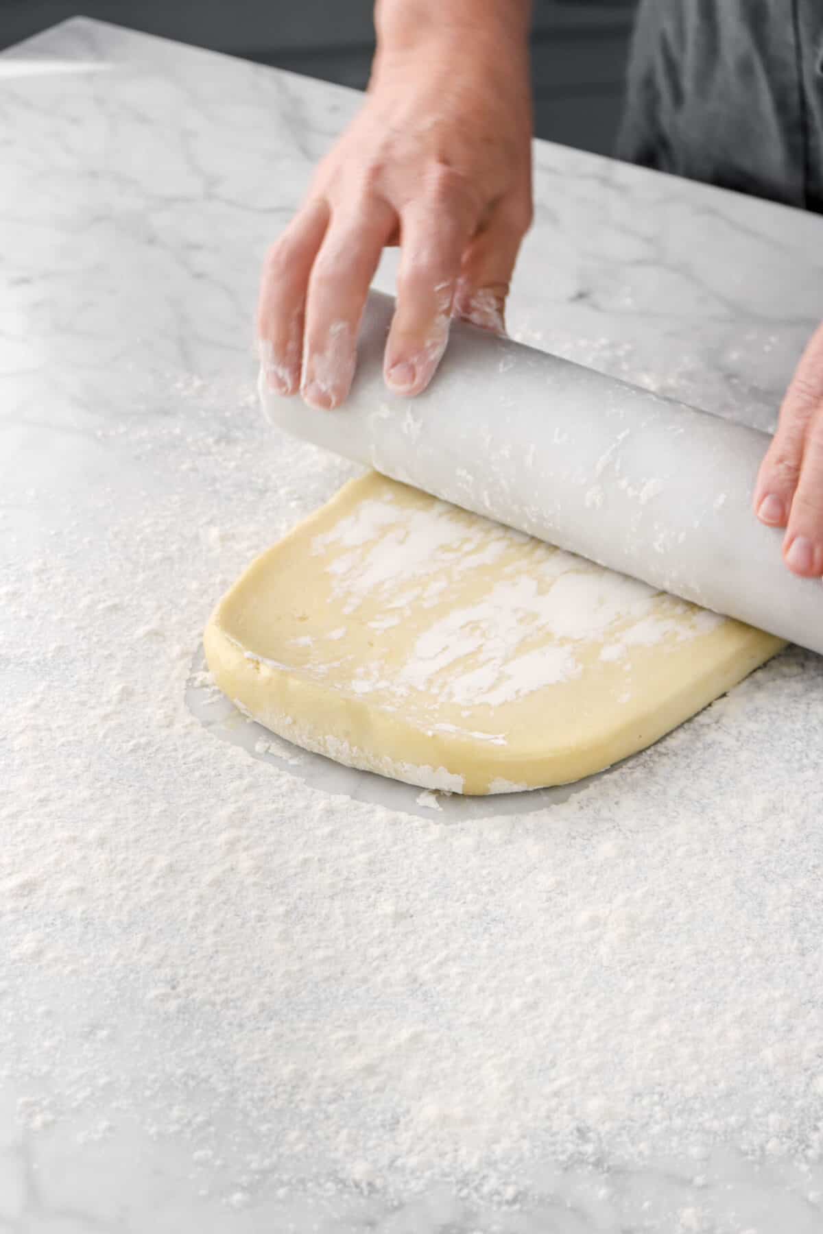 dough being rolled out with marble rolling pin