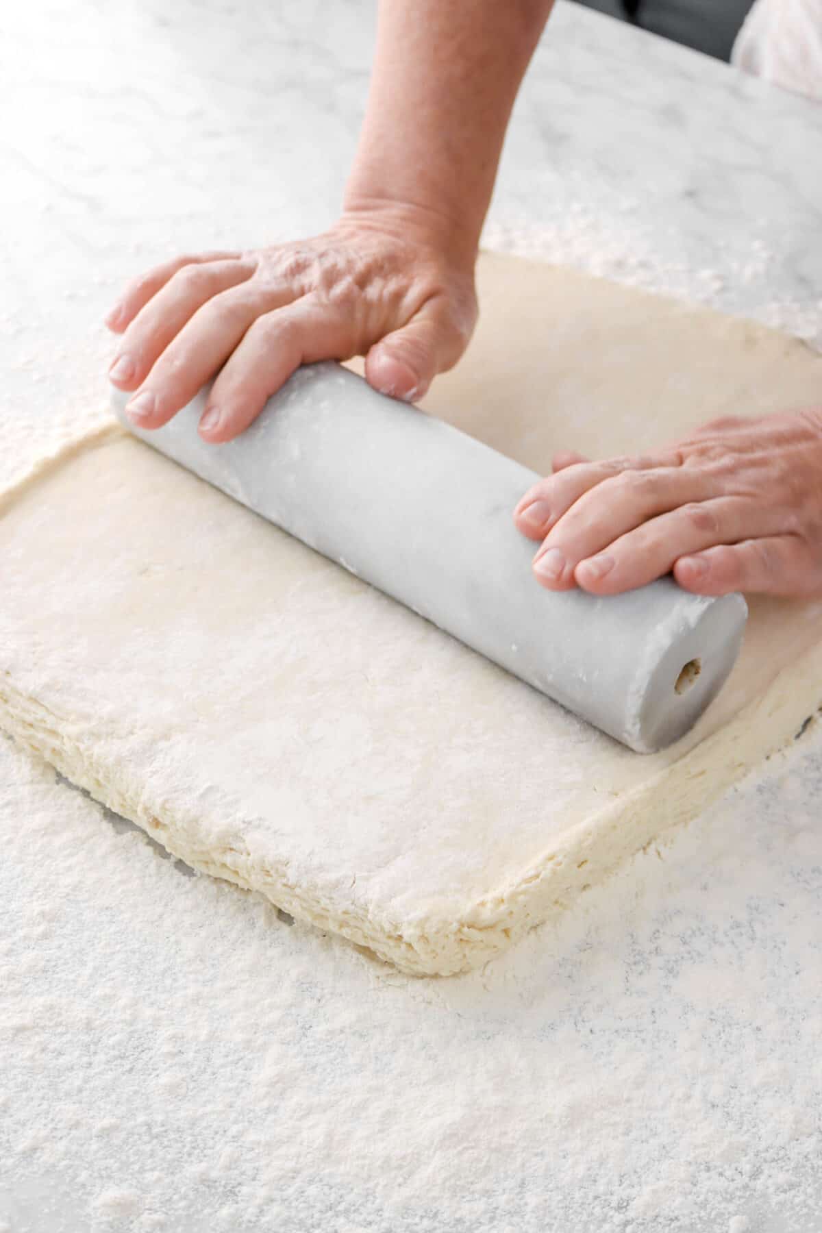 dough being rolled out with marble rolling pin