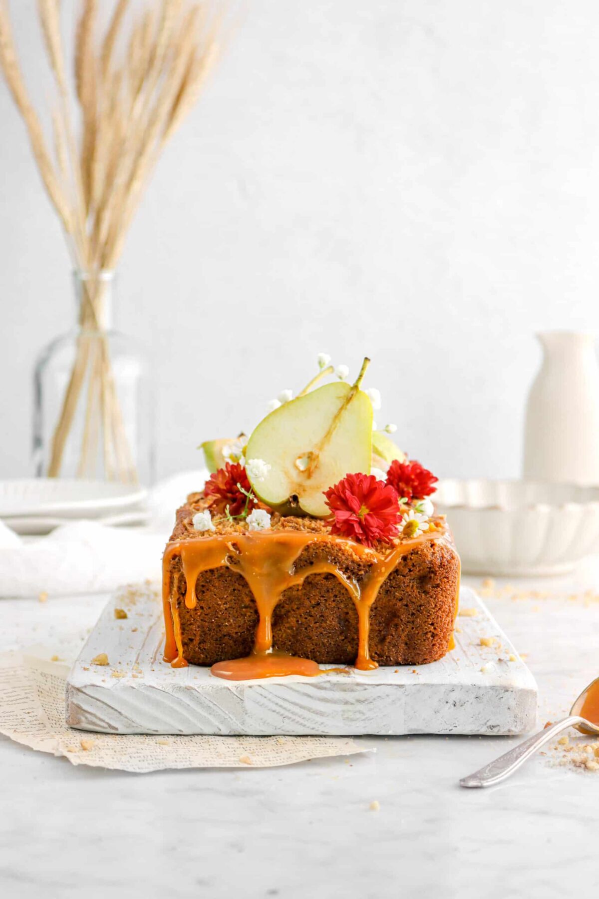 caramel dripping off pear loaf with flowers and sliced pear on top