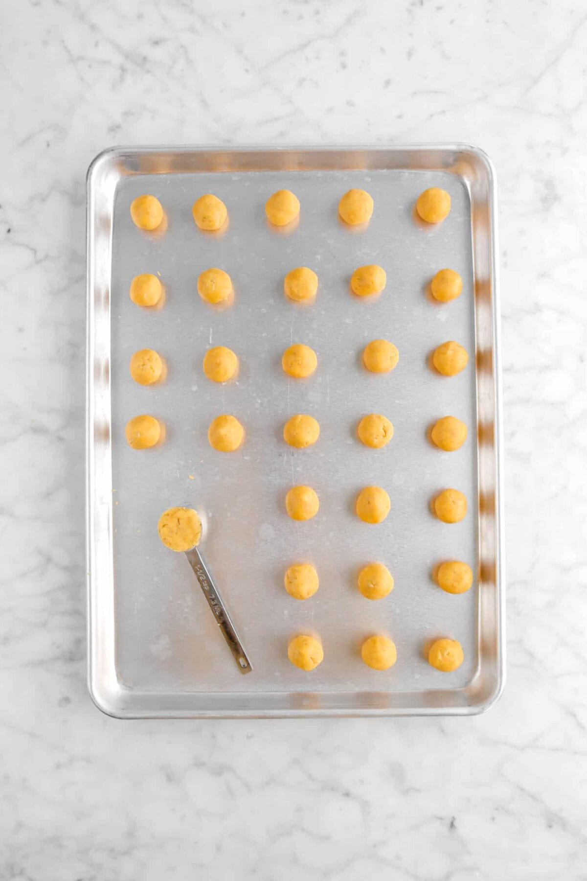 dough balls on sheet pan with teaspoon on pan