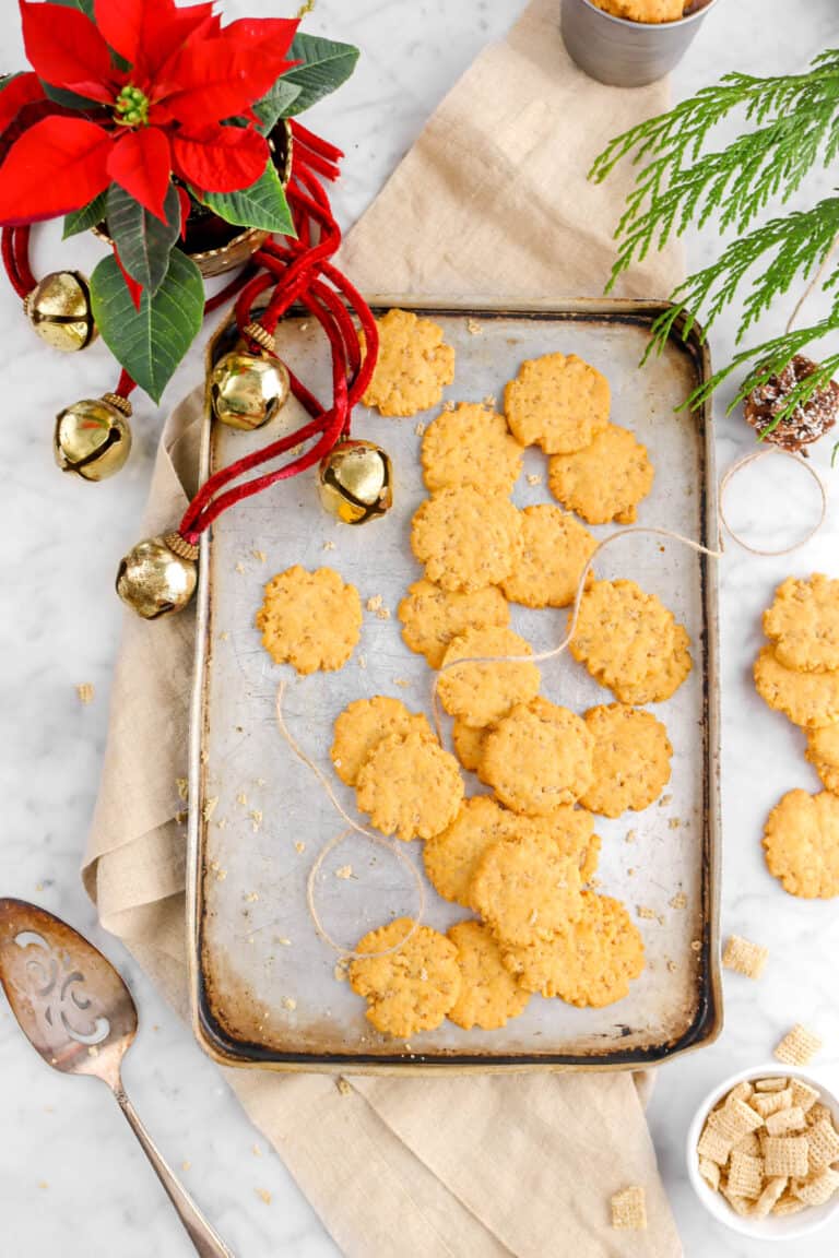 sheet pan full of cheese crakers with christmas decorations around, a tan napkin, and cake knife