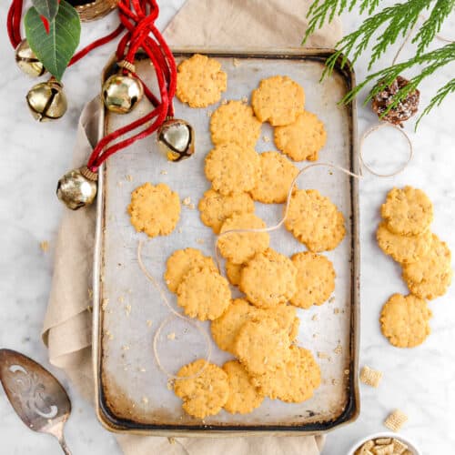 twenty one cheese crackers on mini vintage sheet pan with napkin, more crackers around, christmas greenery, and jingle bells