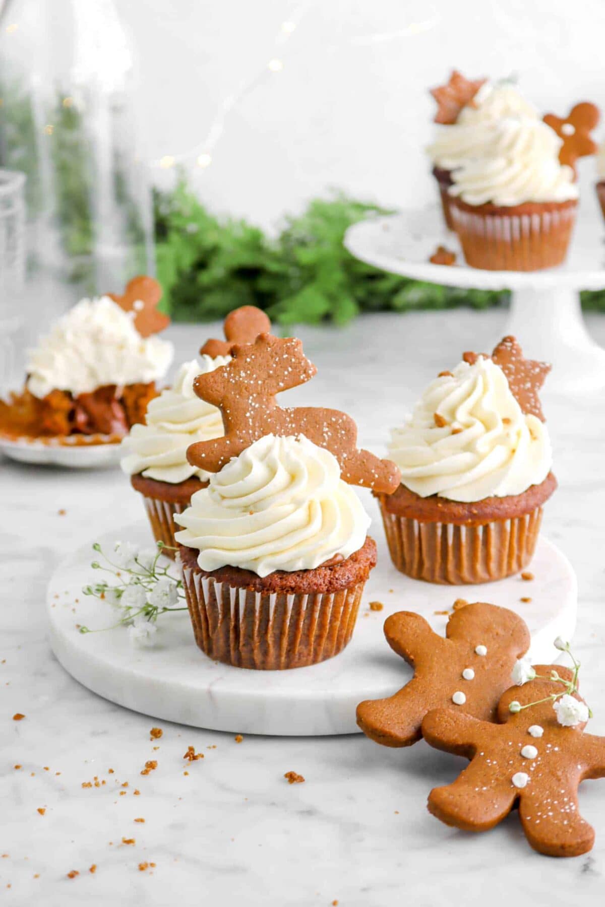 three gingerbread cupcakes with baby's breath flowers, christmas greenery, and cookies