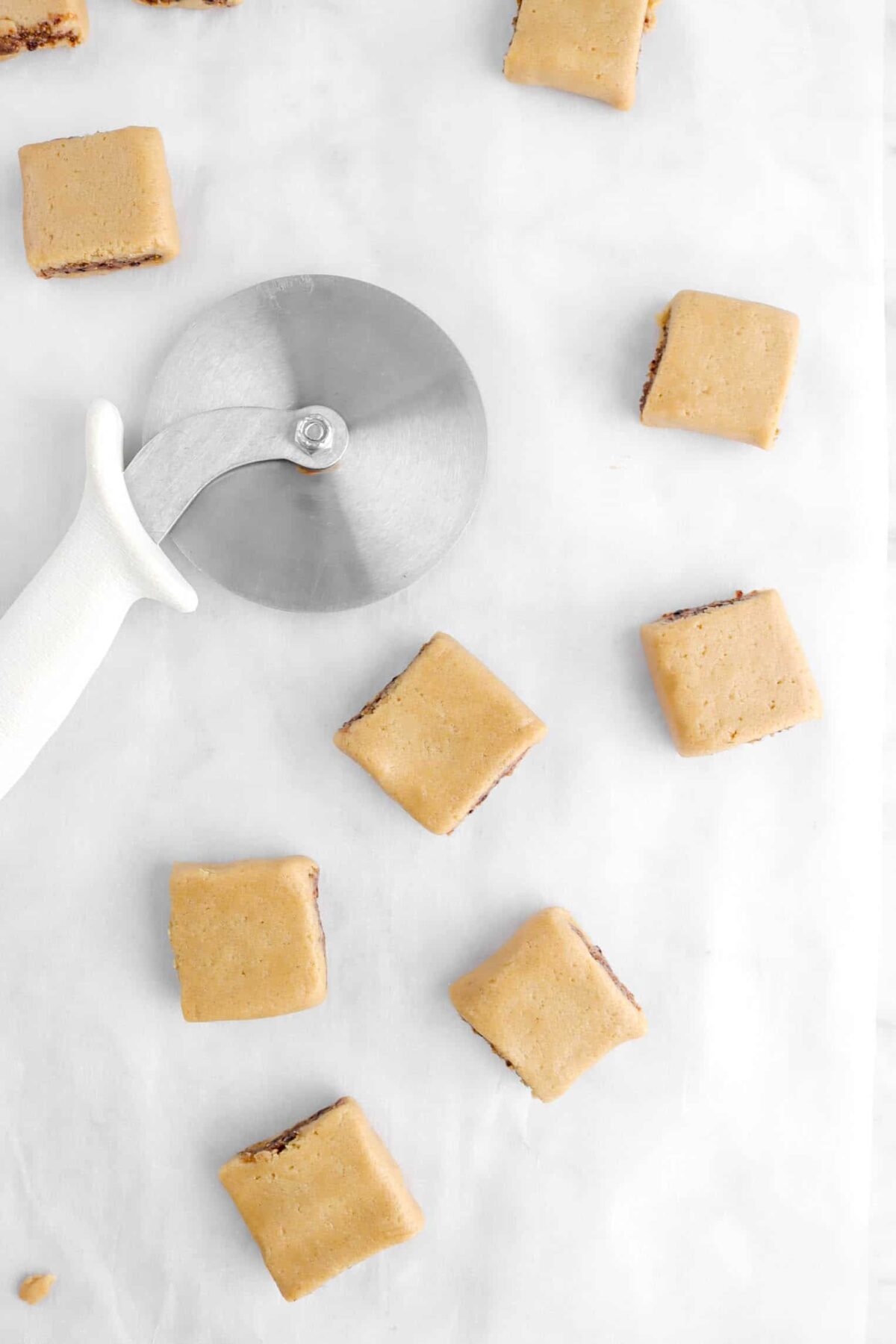 square cookies on parchment paper with pizza cutter