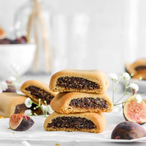 three fig newtons on parchment paper with flowers and fresh figs