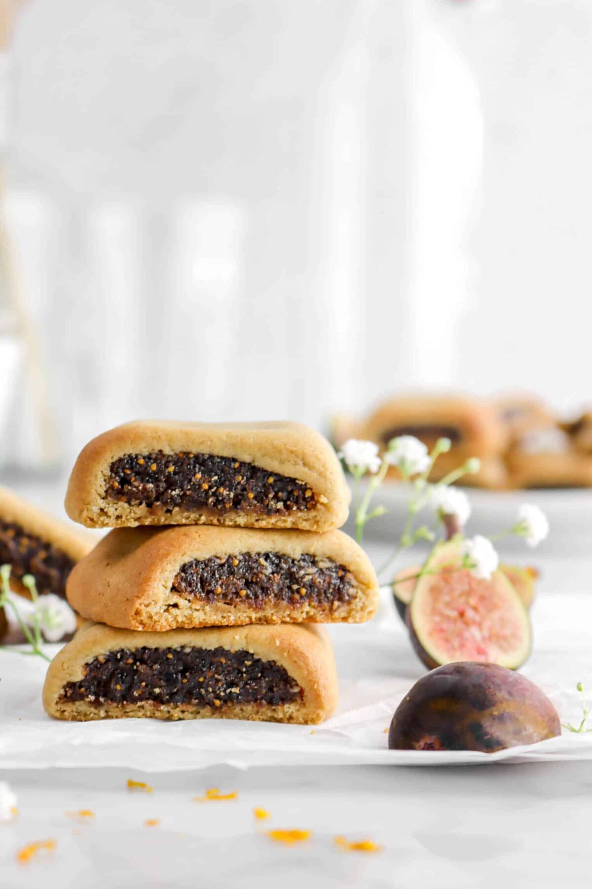 three stacked fig newtons with fresh figs on parchment paper