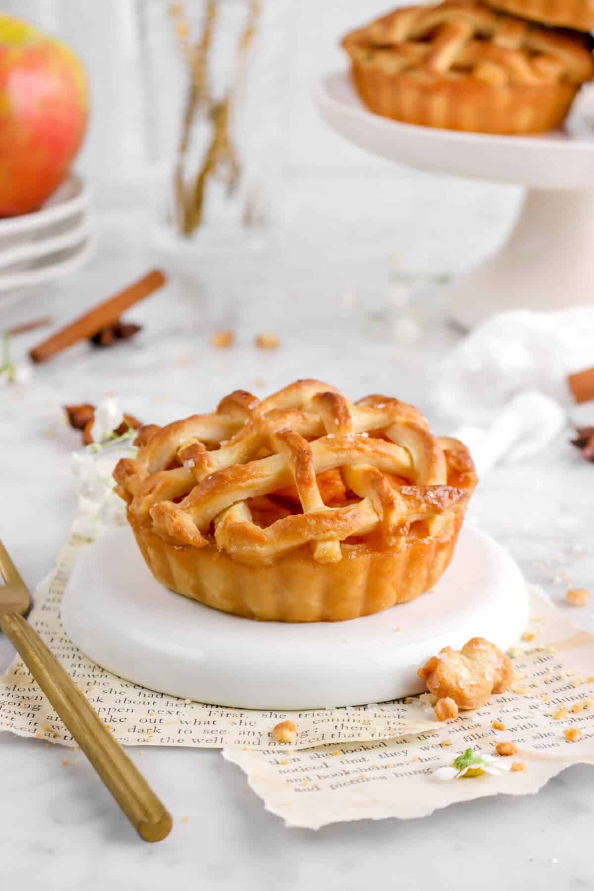 mini pie on plate with gold fork, book pages, and spices around