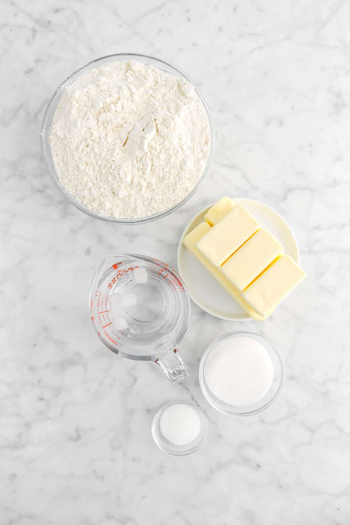 flour, butter, ice water, sugar, and salt on marble counter