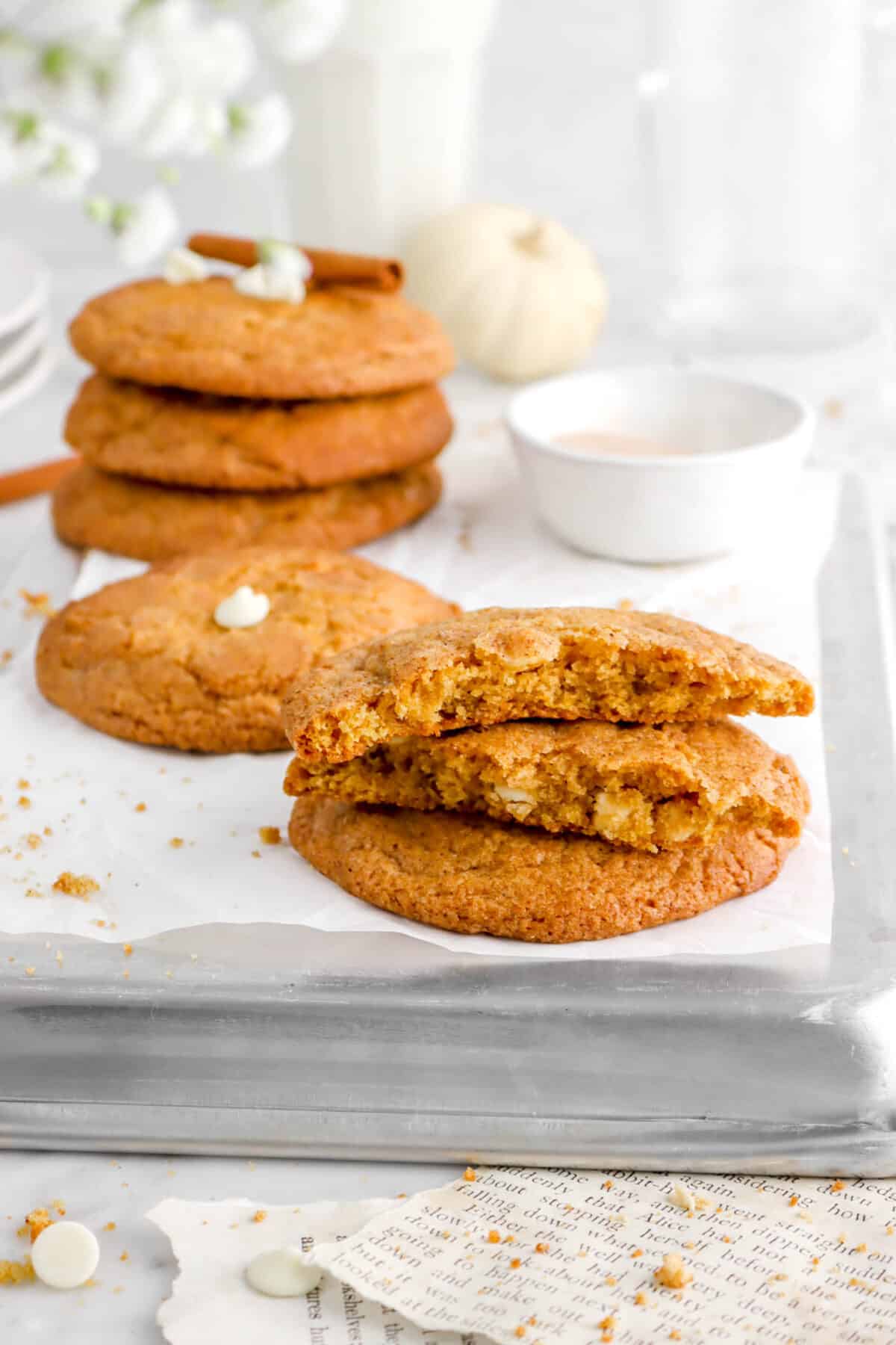 pumpkin snickerdoodle cookies stacked on upside down sheet pan with flowers