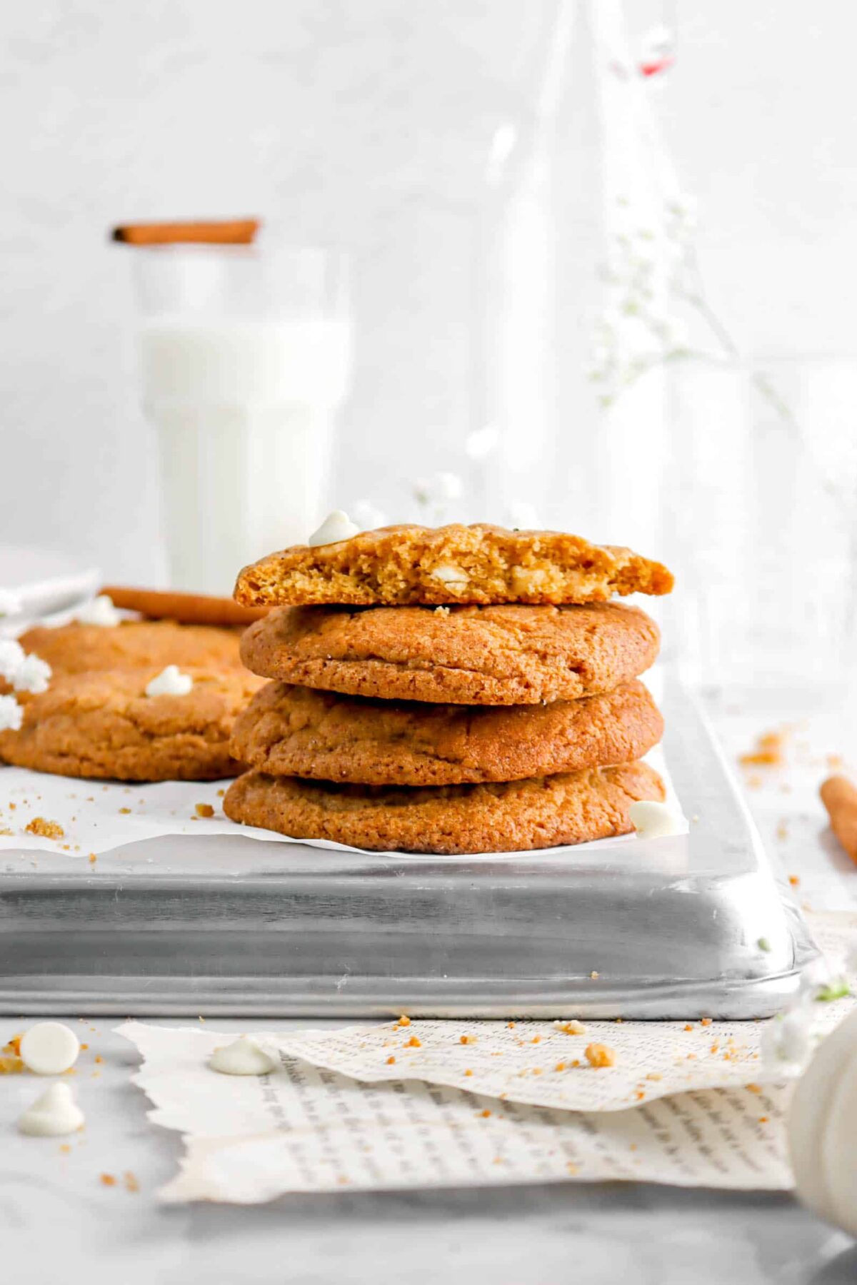 four stacked pumpkin snickerdoodles on upside down sheet pan with glass of milk behind