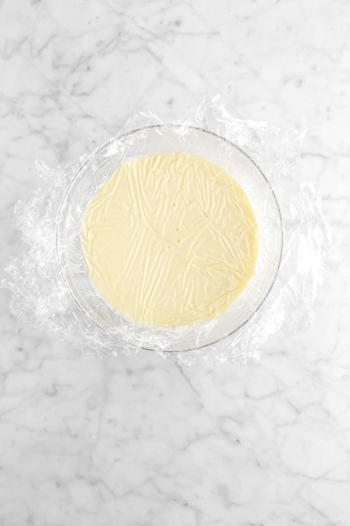 white chocolate mixture covered with plastic wrap in bowl