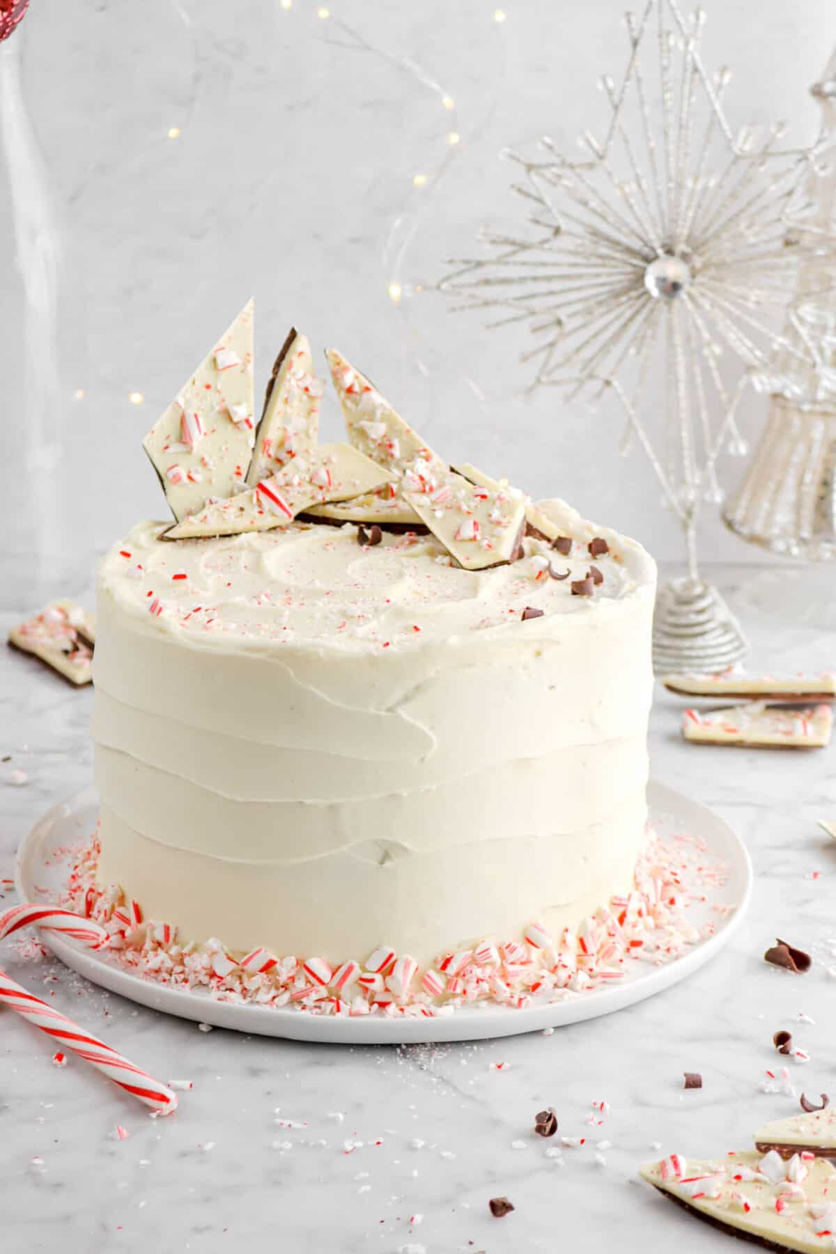 close up of cake on white plate with peppermint bark and crushed candy canes