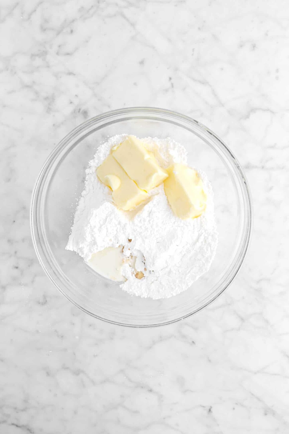 butter, powdered sugar, milk, and vanilla in glass bowl